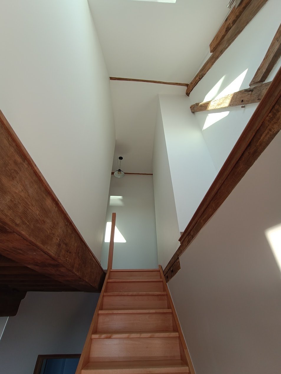 Cage d’escalier rénovée et repeinte autour de poutres apparentes